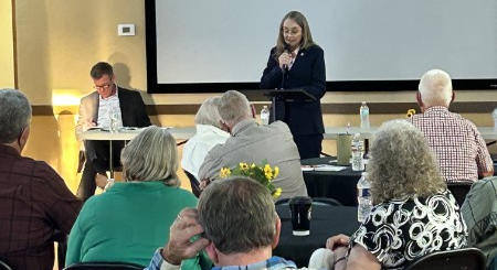 Molly Jenkins speaking at a packed 2025 town hall meeting in Perkins, Oklahoma